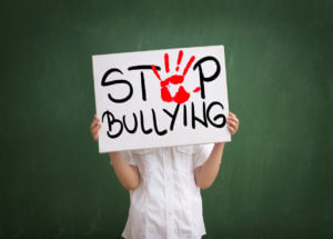 Boy holding a sign with red palm print and text stop bullying