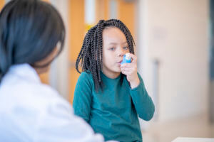 boy using inhaler to treat asthma