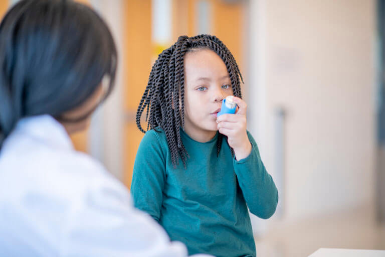 boy using inhaler to treat asthma