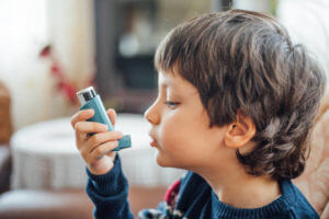 child with asthma holding an asthma inhaler