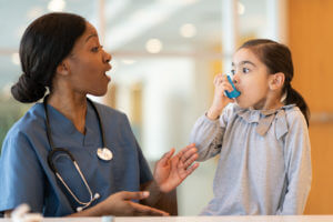 Female doctor assists young asthmatic patient