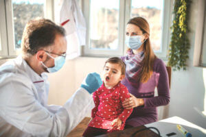 Pediatrician checking little girl's mouth