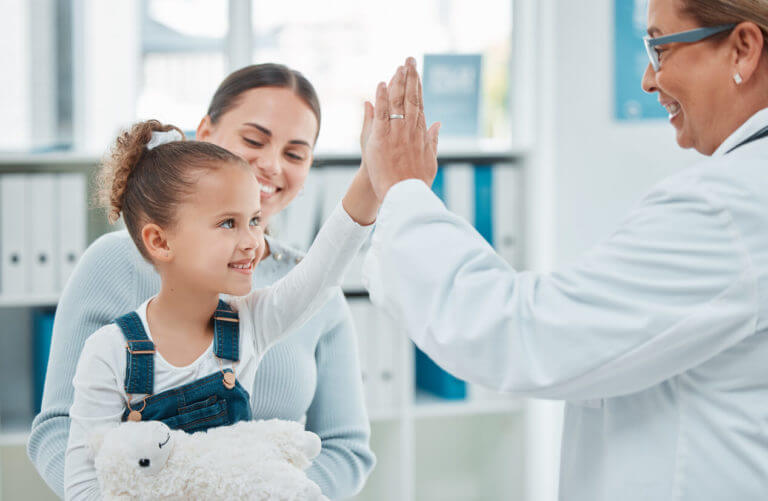 little girl giving a doctor a high five in a clinic
