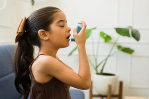 little girl sick with asthma using the inhaler