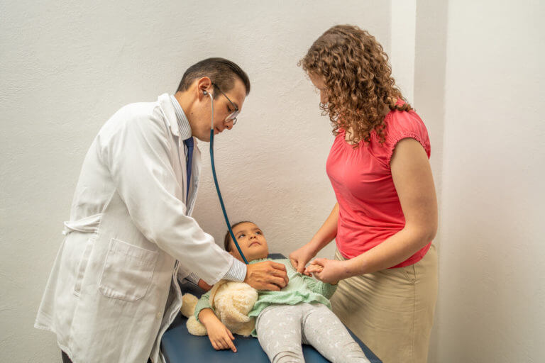 Pediatrician checking on girl belly at sports physical