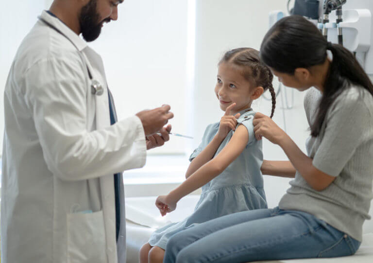 A girl child with her mother is getting ready to receive her pediatric flu shot from a pediatrician.